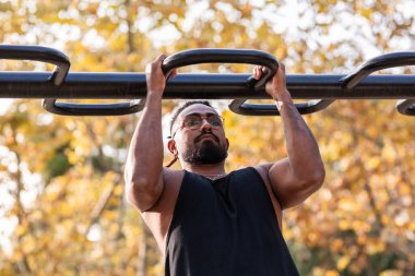 Afrikalı Amerikalı sporcu çocuk parktaki barlarda jimnastik yapıyor.