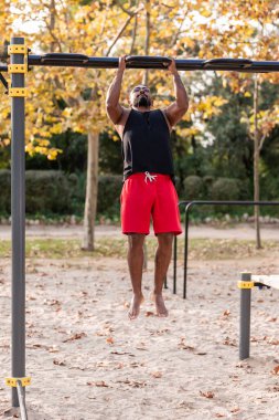 Afrikalı Amerikalı sporcu çocuk parktaki barlarda jimnastik yapıyor.