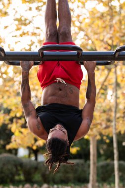 Afrikalı Amerikalı sporcu çocuk parktaki barlarda jimnastik yapıyor.