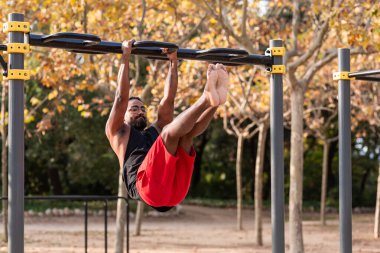 Afrikalı Amerikalı sporcu çocuk parktaki barlarda jimnastik yapıyor.