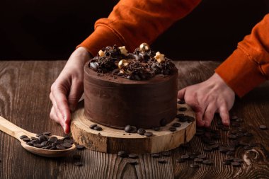 Çikolatalı pasta, çikolata parçacıkları, kaşık tahtası ve iki el.
