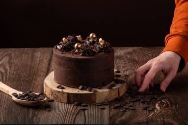 Çikolatalı pastanın önü, çikolata parçacıkları bırakan bir el, kaşık ahşap.