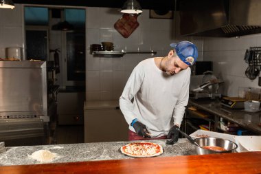 Erkek aşçı İtalyan restoranında pizza hazırlar.
