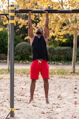 Afrikalı Amerikalı sporcu çocuk parktaki barlarda jimnastik yapıyor.