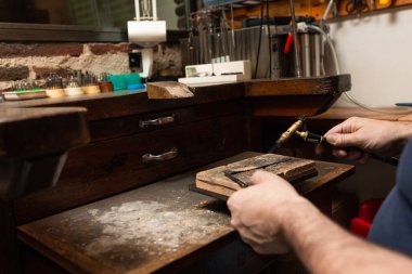 Kuyumcu, yüzük yapmak için bir parça gümüşü gaz feneriyle ısıtır..