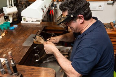 Mücevher yapmak için kuyumcu bir parça metal, gümüş kesiyor..