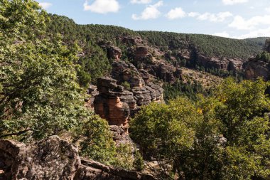 Sonbaharda ormanı olan kayalık dağların manzarası güneşli bir günde bulutlarla kaplı.