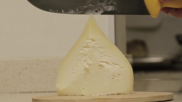 O queijo de tetilla galego corta-se com uma faca por umas mãos de mulher em uma cozinha. — Vídeo de Stock