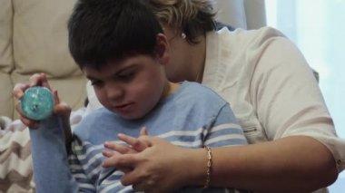 Özürlü bir çocuk annesinin kucağında, lastik bir topla oynuyor..