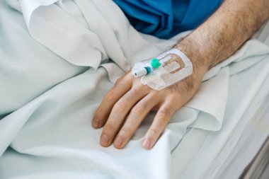 Damardan kanülü hasta eli hastane yatağında tedavi görüyor. Sağlık, hastalık ve iyileşme konsepti