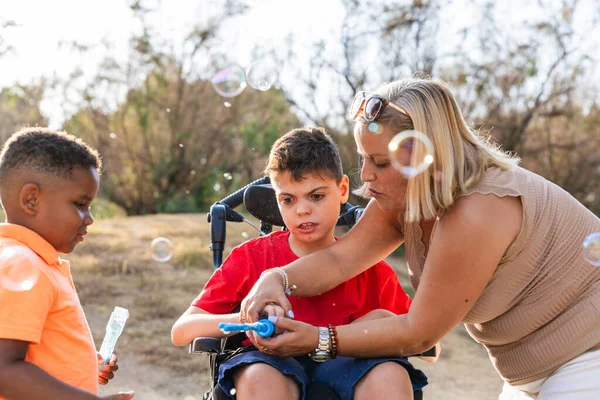 Hademe, tekerlekli sandalyedeki farklı bir çocuğa yardım ediyor. Başka bir çocukla dışarıda oynuyor.
