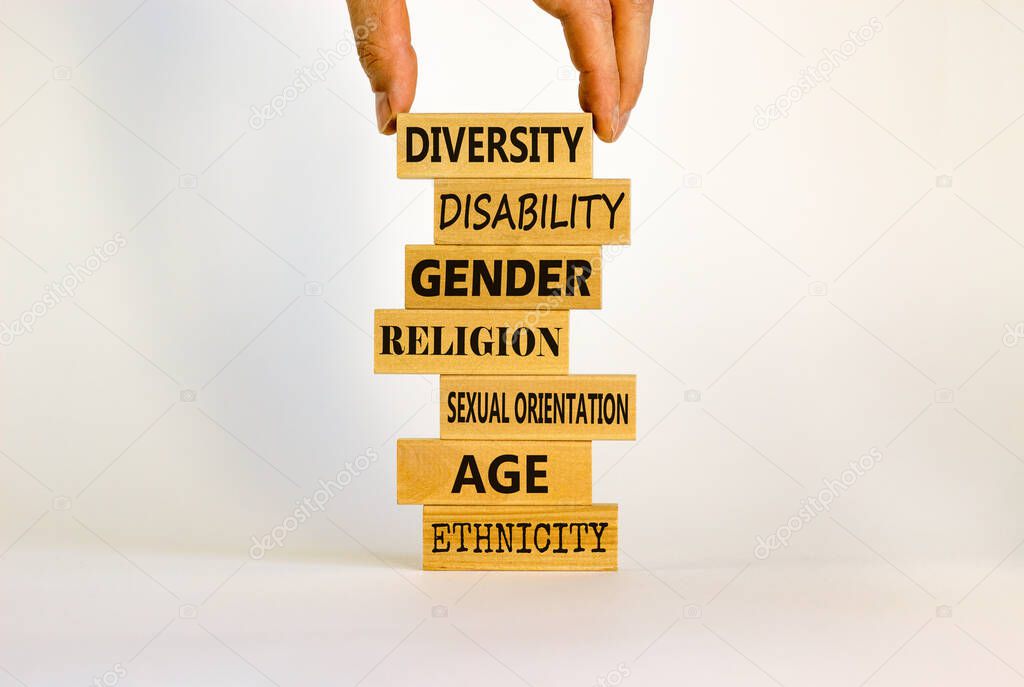 Diversity ethnicity gender age sexual orientation religion disability words written on wooden block. Male hand. Beautiful white background. Equality and diversity concept.