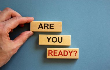 Erkek el bir bloğu 'are' sözcüğüyle bir blok kulesinin tepesine 'hazır mısın' sözleriyle yerleştiriyor. Güzel mavi arka plan. Uzayı kopyala İş konsepti.