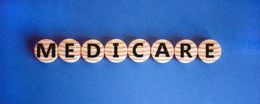 Wooden circles with word 'medicare'. Beautiful blue background. Medical concept. Copy space. clipart