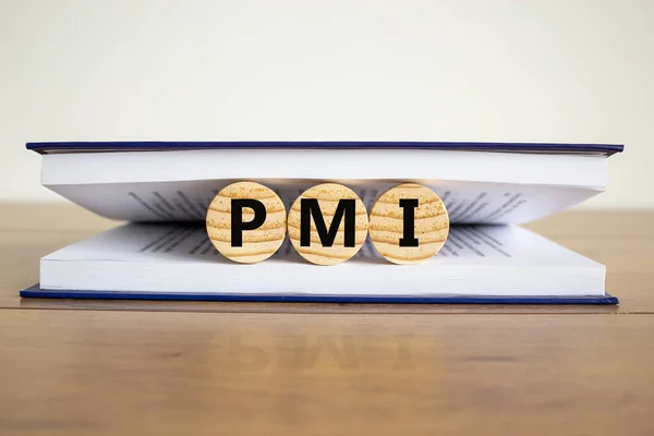 Concept word \'PMI - purchasing manager index, \' on wooden circles between pages of a book on a beautiful wooden table. White background. Business concept.