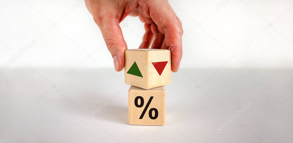 Male hand turns the wooden cubes changes the direction of an arrow symbolizing that the interest rates are going down or vice versa . Business concept. Beautiful white background, copy space.