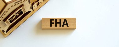 'FHA' sözcüğüyle tahta blok, minyatür evin yanında federal iskan idaresi. Güzel beyaz arka plan, kopyalama alanı. iş kavramı.