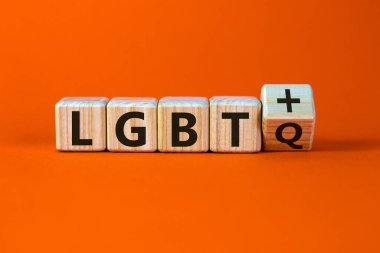 Zar, 'LGBTQ' ve 'LGBT +' kısaltmalarını oluşturur. Erkek eli. Güzel turuncu arka plan. Kavram, kopyalama alanı.