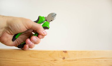 Bir erkek eli, tahta bir çubukta tel kesiciyi tutuyor. Güzel beyaz arka plan. Uzayı kopyala Kavram.