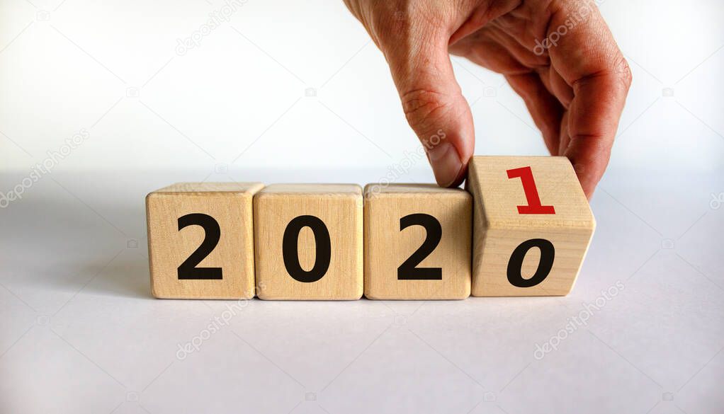 Business concept of planning 2021. Male hand flips wooden cube and change the inscription '2020' to '2021'. Beautiful white background, copy space.