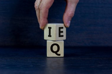 Elle bir küp çevirir ve 'IQ - zeka katsayısı' ifadesini 'EQ - duygusal katsayısı' olarak değiştirir. Güzel koyu ahşap arka plan. Psikolojik konsept. Boşluğu kopyala.