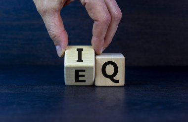 Elle bir küp çevirir ve 'IQ - zeka katsayısı' ifadesini 'EQ - duygusal katsayısı' olarak değiştirir. Güzel koyu ahşap arka plan. Psikolojik konsept. Boşluğu kopyala.