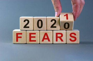 İş planı 2021. Erkek el ahşap bir küpü çevirir ve '2020 Korkusu' yazısını '2021 Korkusu' olarak değiştirir. Güzel gri arkaplan, kopyalama alanı.