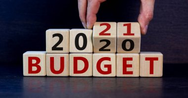 İş planı 2021. Erkek eli ahşap küpleri çevirir ve 'Budget 2020' yazısını 'Budget 2021' olarak değiştirir. Güzel koyu ahşap arkaplan, kopyalama alanı.