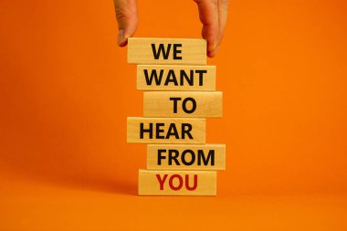 Wooden blocks with words 'we want to hear from you'. Male hand. Beautiful orange background. Copy space. Business concept. clipart