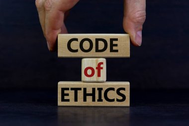 Erkek el, blok kulesine 'kod' kelimesi ile 'ahlak kuralları' yazan bir blok yerleştiriyor. Güzel, koyu, ahşap arka plan. Uzayı kopyala İş konsepti.