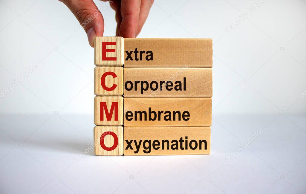 Concept words 'ECMO, Extra Corporeal Membrane Oxygenation' on cubes and blocks on a beautiful white background. Male hand. Copy space. Medical concept.