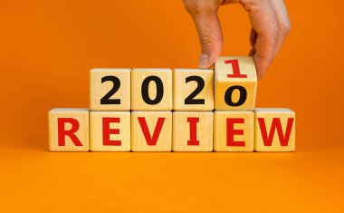İş planı 2021. Erkek el ahşap küpü çevirir ve '2020 Gözden Geçir' yazısını '2021' e çevirir. Güzel turuncu arkaplan, kopyalama alanı.