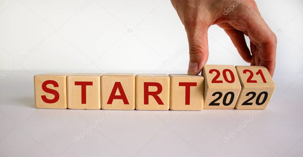 Business concept of starting 2021. Male hand flips wooden cubes and changes the inscription 'Start 2020' to 'Start 2021'. Beautiful white background, copy space.