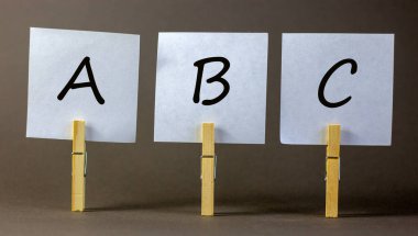 A, B ve C harfleriyle beyaz kağıtlı ahşap mandallar. Güzel gri arka plan. İş ve eğitim kavramı, kopyalama alanı.