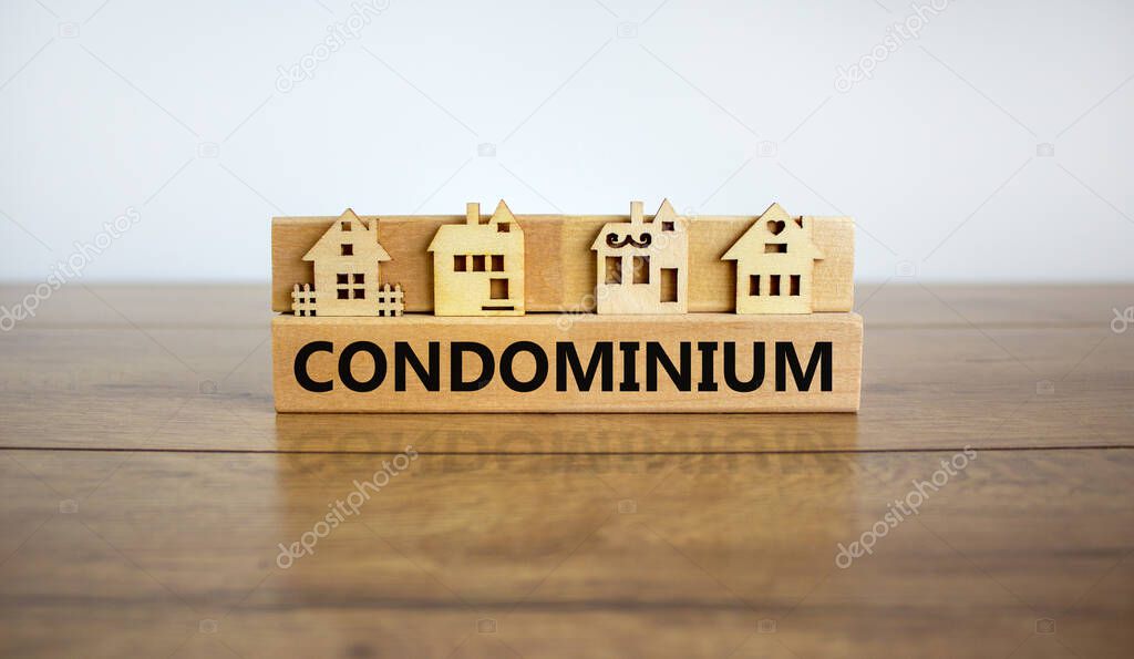 Block form the word 'condominium' in front of a miniature house. Business concept, copy space.