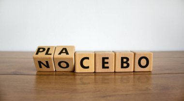 Nocebo veya plasebo. Küplere dönüştü ve 'plasebo' kelimesini 'nocebo' ya çevirdi, ya da tam tersi. Güzel ahşap masa, beyaz arka plan, fotokopi alanı. Tıp ve bilim konsepti.