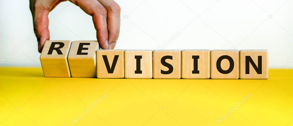 Time to revision. Hand turns cubes and changes the word 'vision' to 'revision' or vice versa. Beautiful yellow table, white background. Business and revision concept, copy space.