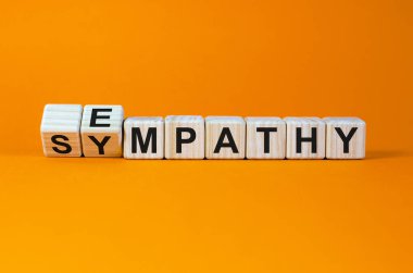 Erom sympathy to empathy. Turned cubes and changed the word 'sympathy' to 'empathy'. Beautiful orange background. Copy space. Psychological, sympathy and empathy concept. clipart