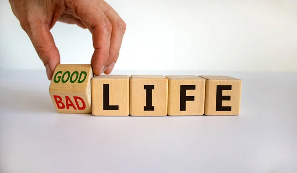 From bad to good life. Hand is turning a cube and changes the words \'bad life\' to \'good life\'. Beautiful white background. Business and good life concept, copy space.