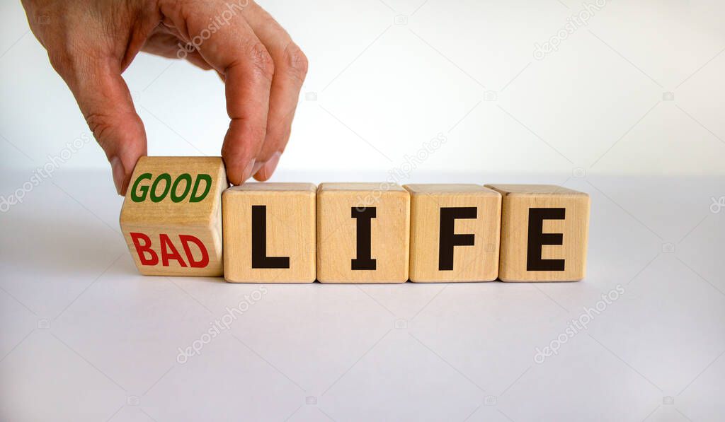 From bad to good life. Hand is turning a cube and changes the words 'bad life' to 'good life'. Beautiful white background. Business and good life concept, copy space.