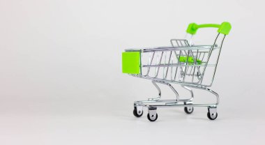 Alışveriş zamanı. Beyaza izole edilmiş boş minyatür alışveriş arabası. Yakın çekim, yan görüş. Güzel beyaz arka plan, kopyalama alanı. Alışveriş konsepti.