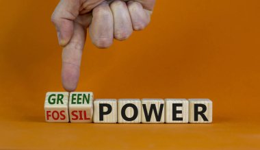 Grom fosilinden yeşil güce. Erkek el küpleri dönüştürür ve 'fosil güç' kelimesini 'yeşil güç' e çevirir. Güzel turuncu arka plan. İş ve yeşil güç kavramı. Boşluğu kopyala.