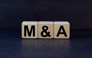Mergers and acquisitions symbol. Concept words 'M and A - Mergers and acquisitions' on wooden cubes on a beautiful dark background. Business, mergers and acquisitions concept. Copy space.