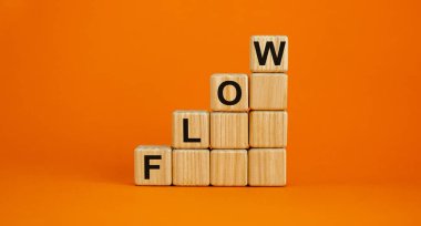 Flow symbol. Wood cubes with word 'flow' stacking as step stair on beautiful orange background, copy space. Business and flow concept.