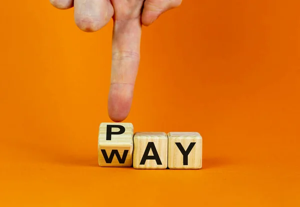 Way to pay symbol. Businessman hand turns a cube and changes the word \'way\' to \'pay\'. Business and way to pay concept. Beautiful orange background, copy space.