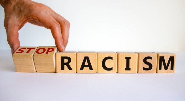 Stop racism symbol. Male hand turns cubes with words 'stop racism'. Beautiful white background. Business and stop racism concept. Copy space.