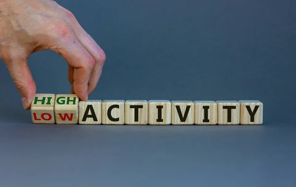 High or low activity symbol. Businessman hand turns cubes and changes words 'low activity' to 'hugh activity'. Business and high activity concept. Beautiful white background, copy space.