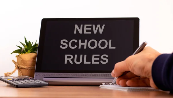 New school rules symbol. Tablet with words \'New school rules\'. Online education during COVID-19 quarantine. Male hand with pen, calculator, copy space. New school rules concept.