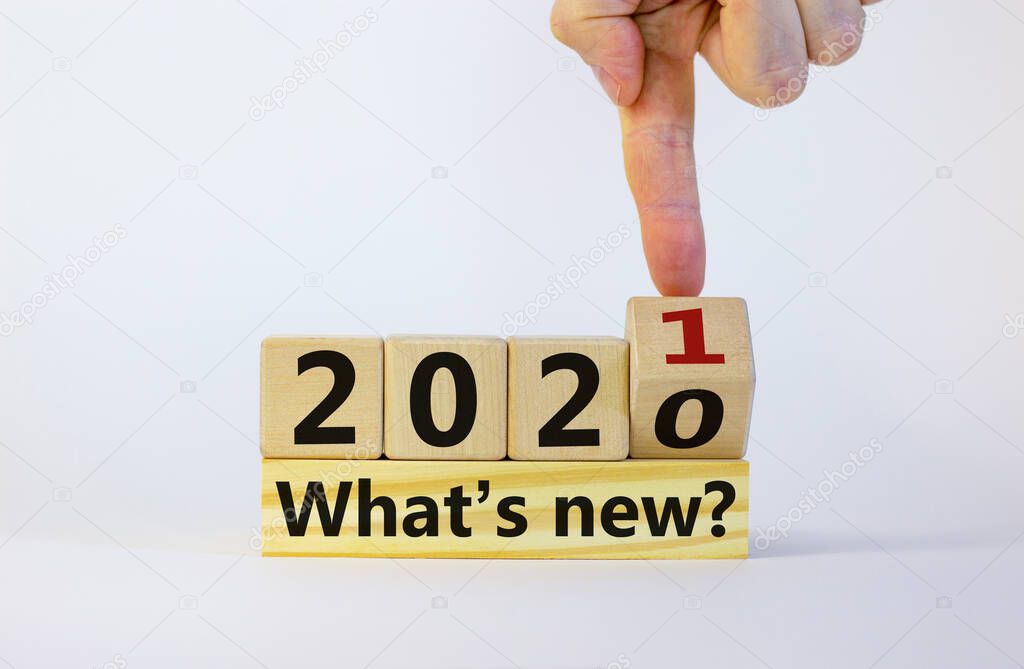 2021 new year symbol. Fliped wooden cube with words '2020, 2021, what is new'. Male hand. Beautiful white background, copy space. Business and 2021 what is new concept.