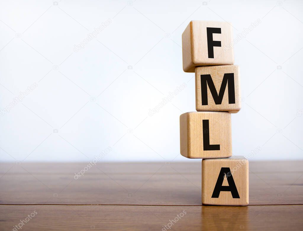 FMLA symbol. Concept words 'FMLA, family medical leave act' on wooden cubes on a beautiful wooden table, white background. Copy space. Medical and FMLA concept.